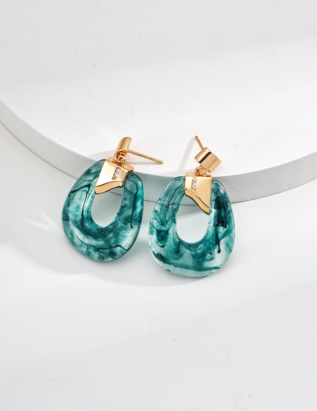 Teal hoop earrings with gold accents on a white background