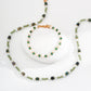 Necklace and bracelet set with green beads on a white background