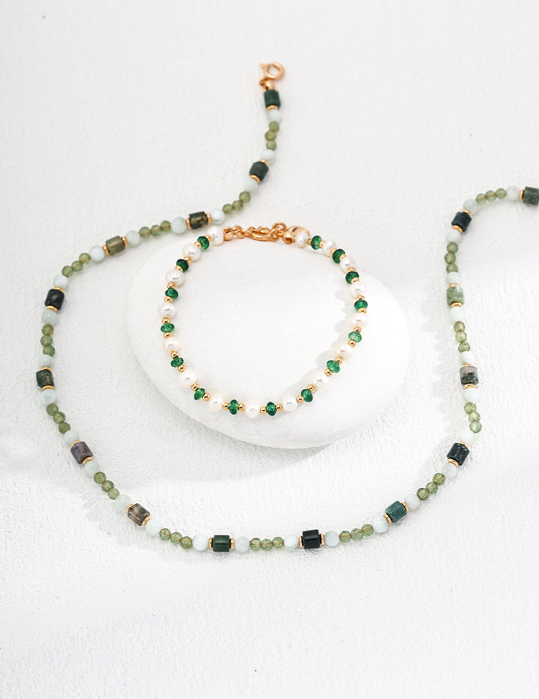 Necklace and bracelet set with green beads on a white background