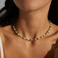 A model wearing an art-gallery style beaded strand necklace featuring multi-shaped natural green moss agates, faceted micro beads, and earth-tone stone cylinders