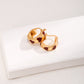 Gold hoop earrings with red hearts on a white surface