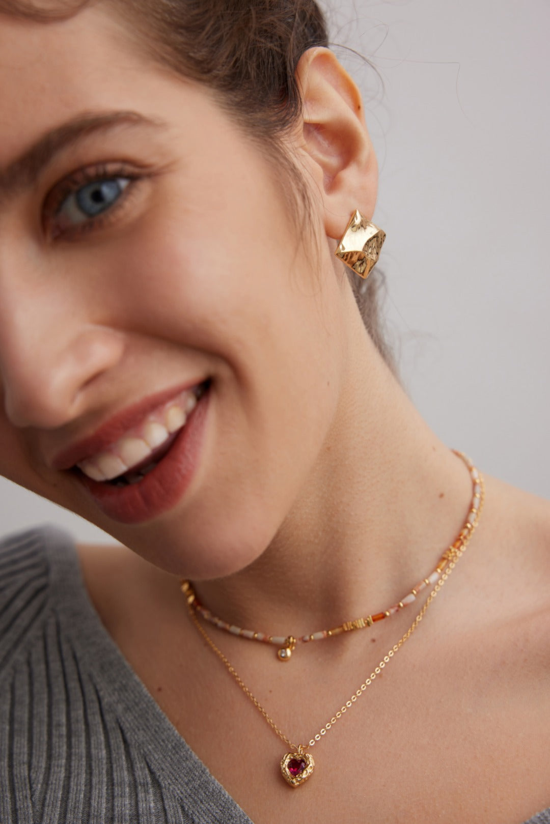 A model wearing an avant-garde geometric choker necklace featuring a rare red and white tartan grid pattern natural agate pendant held by a sparkling micro-pavé cz bail