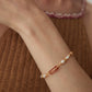 A model wearing a luxury 18k gold plated bracelet featuring rice freshwater pearls, crimson red enamel oblong links, and an adjustable chain slider closure