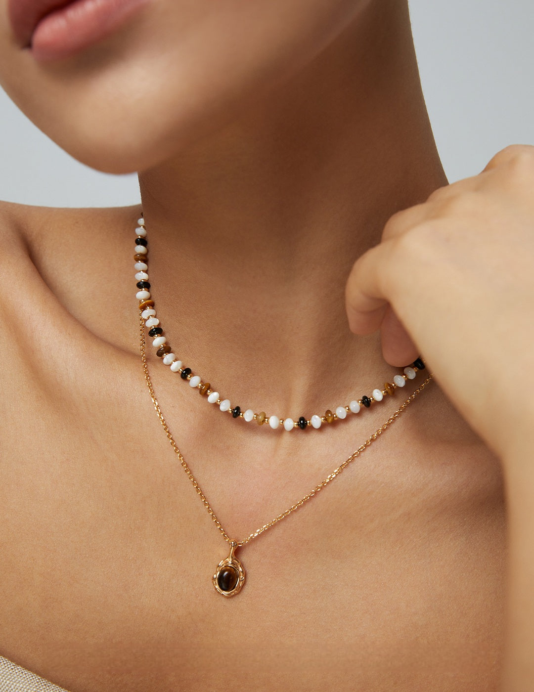 A model wearing an organic molten gold framed round tiger's eye pendant necklace