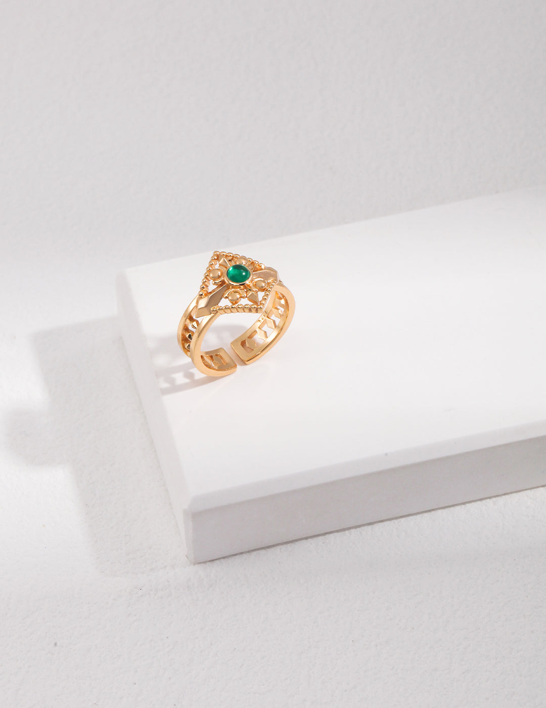 Gold ring with a green gemstone on a white surface