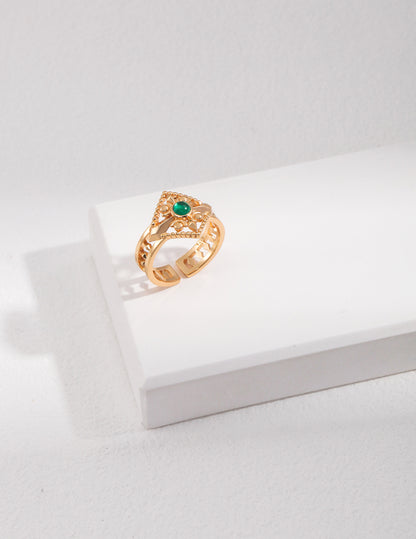 Gold ring with a green gemstone on a white surface