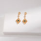 Gold earrings with green gemstones on a white surface