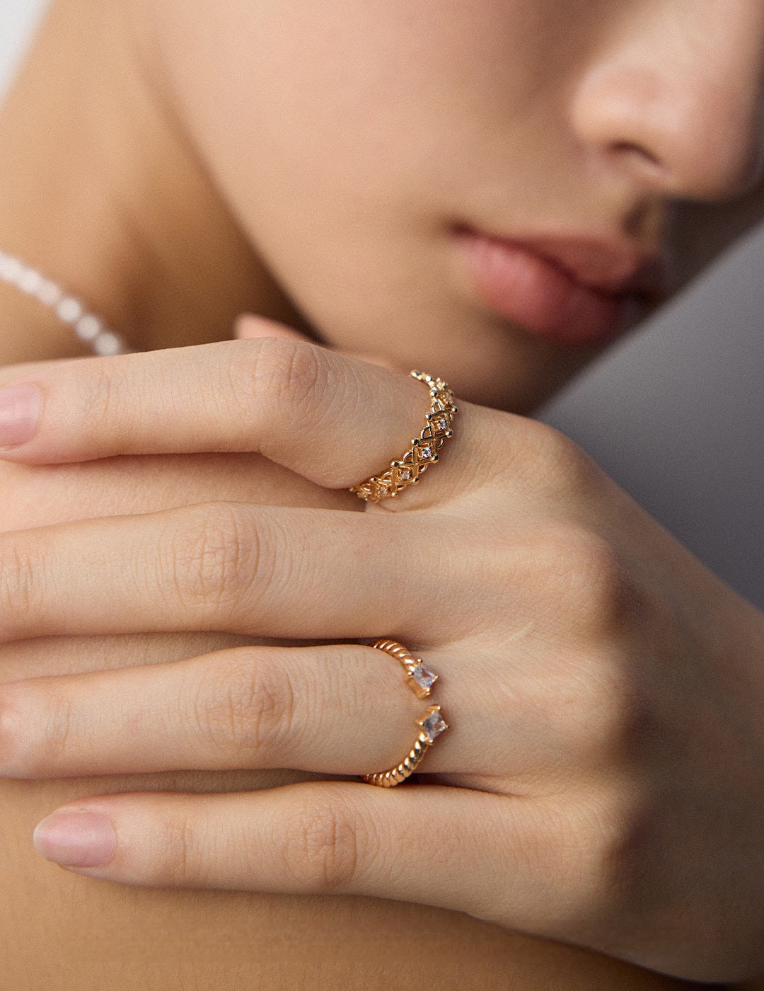Close-up of a person's hand wearing two gold rings with a soft focus background