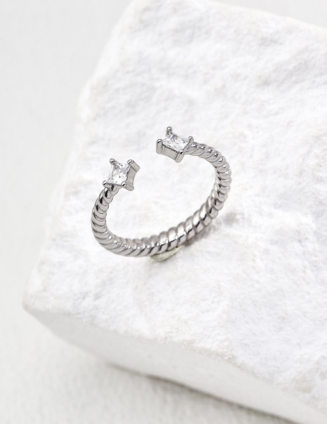 Contemporary minimalist open-band cuff ring in silver finishes featuring radiant prong-set cz gems flanking both open ends