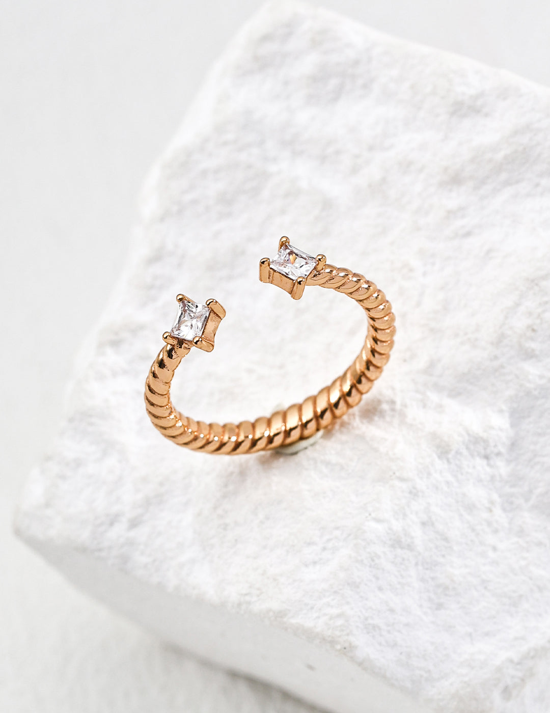 Contemporary minimalist open-band cuff ring in gold finishes featuring radiant prong-set cz gems flanking both open ends