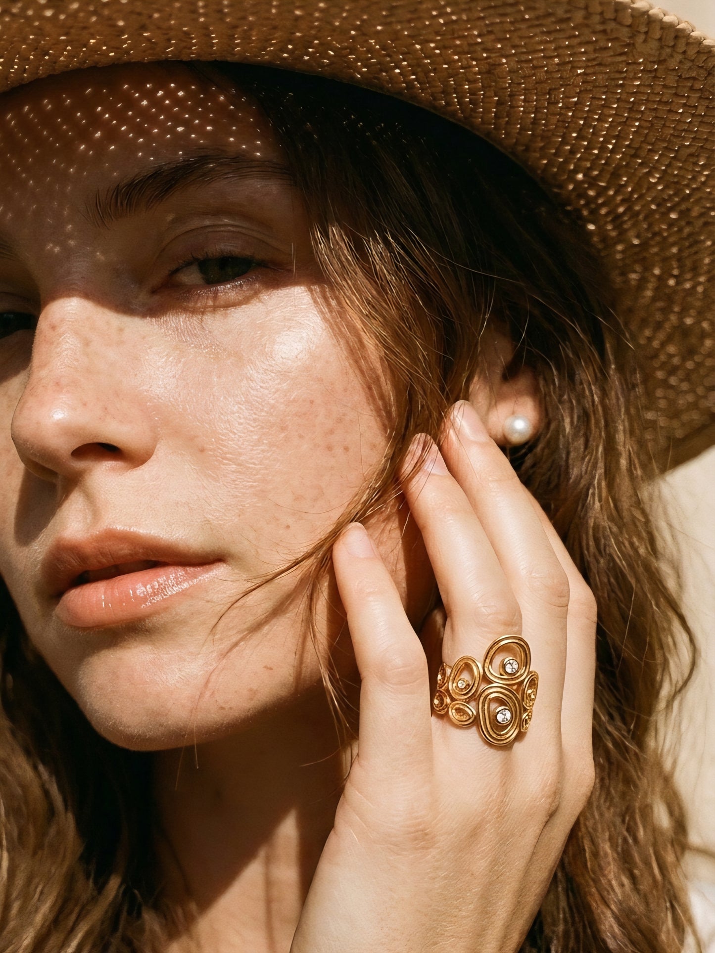 A model wearing a statement wide hollow open adjustable rings featuring artistic fluid cells and embedded cz crystals in gold